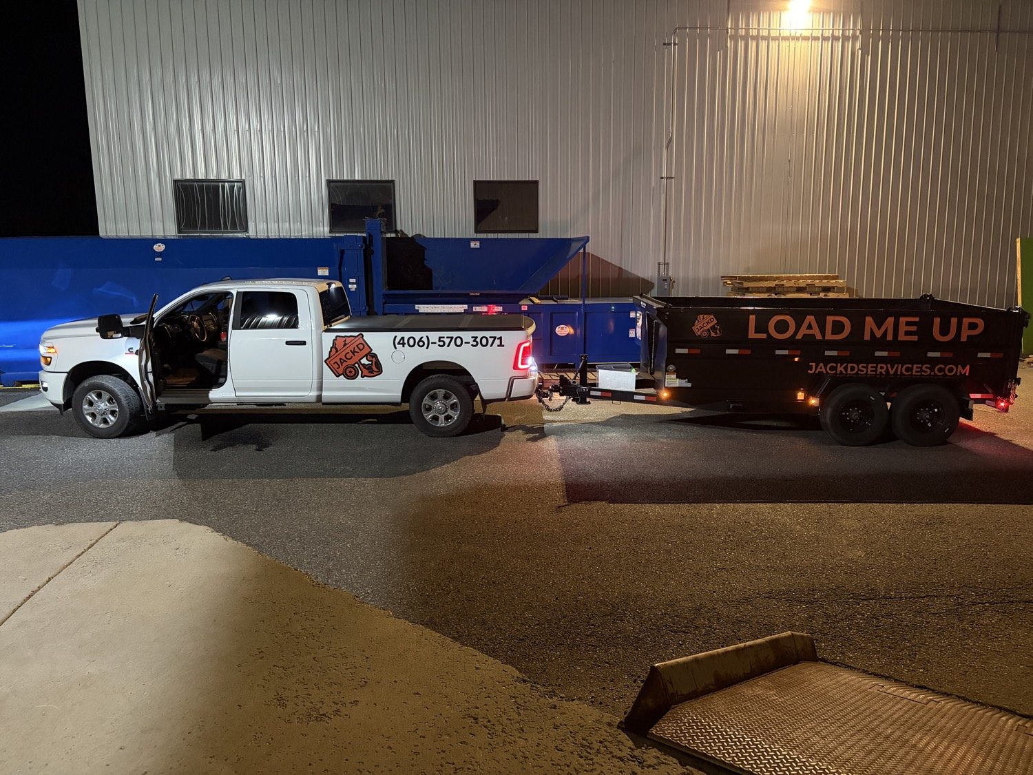 JACKD Ram truck towing a black dump trailer that reads LOAD ME UP