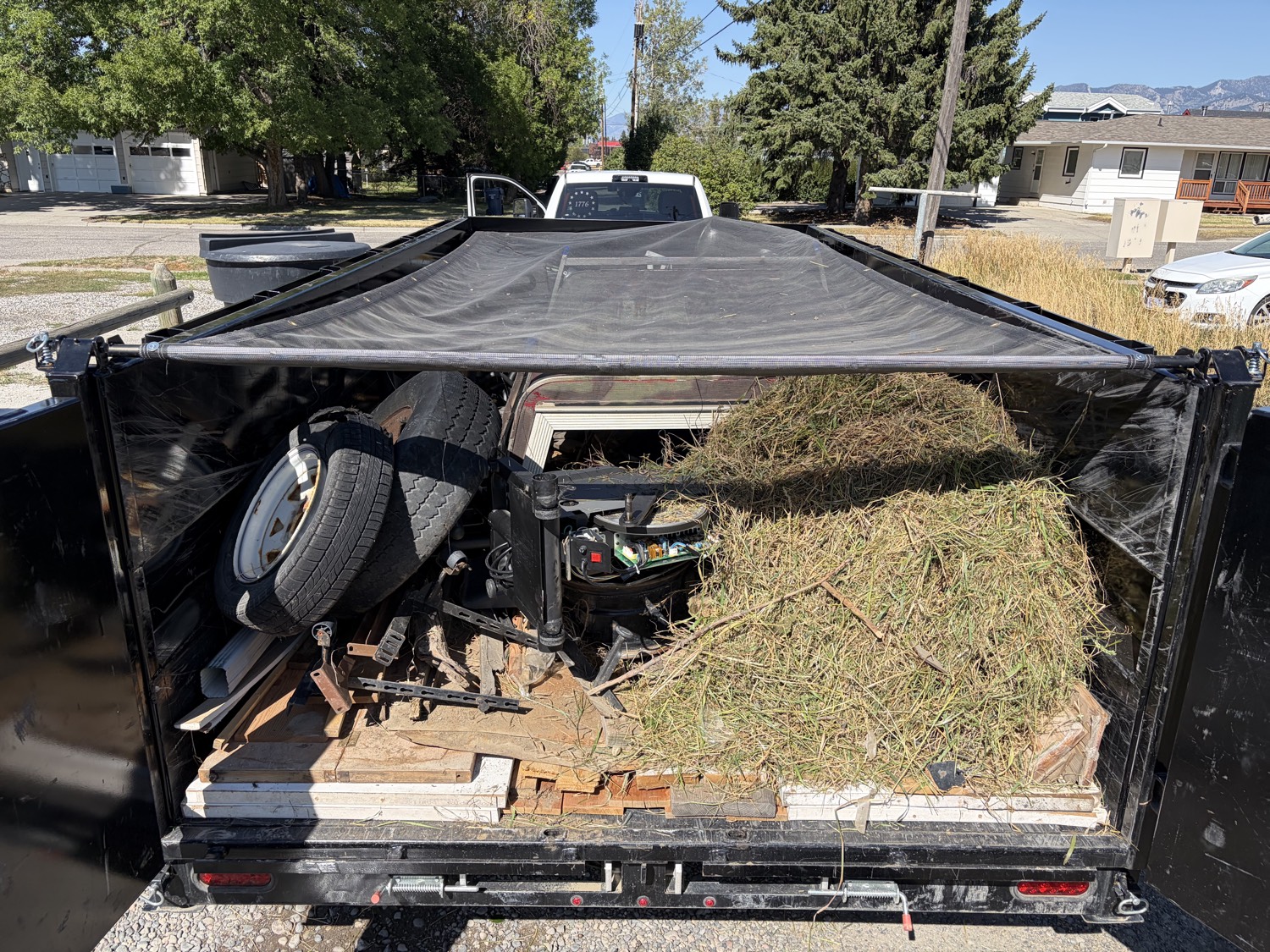 Dump trailer loaded with tires, yard waste, wood, and mixed junk
