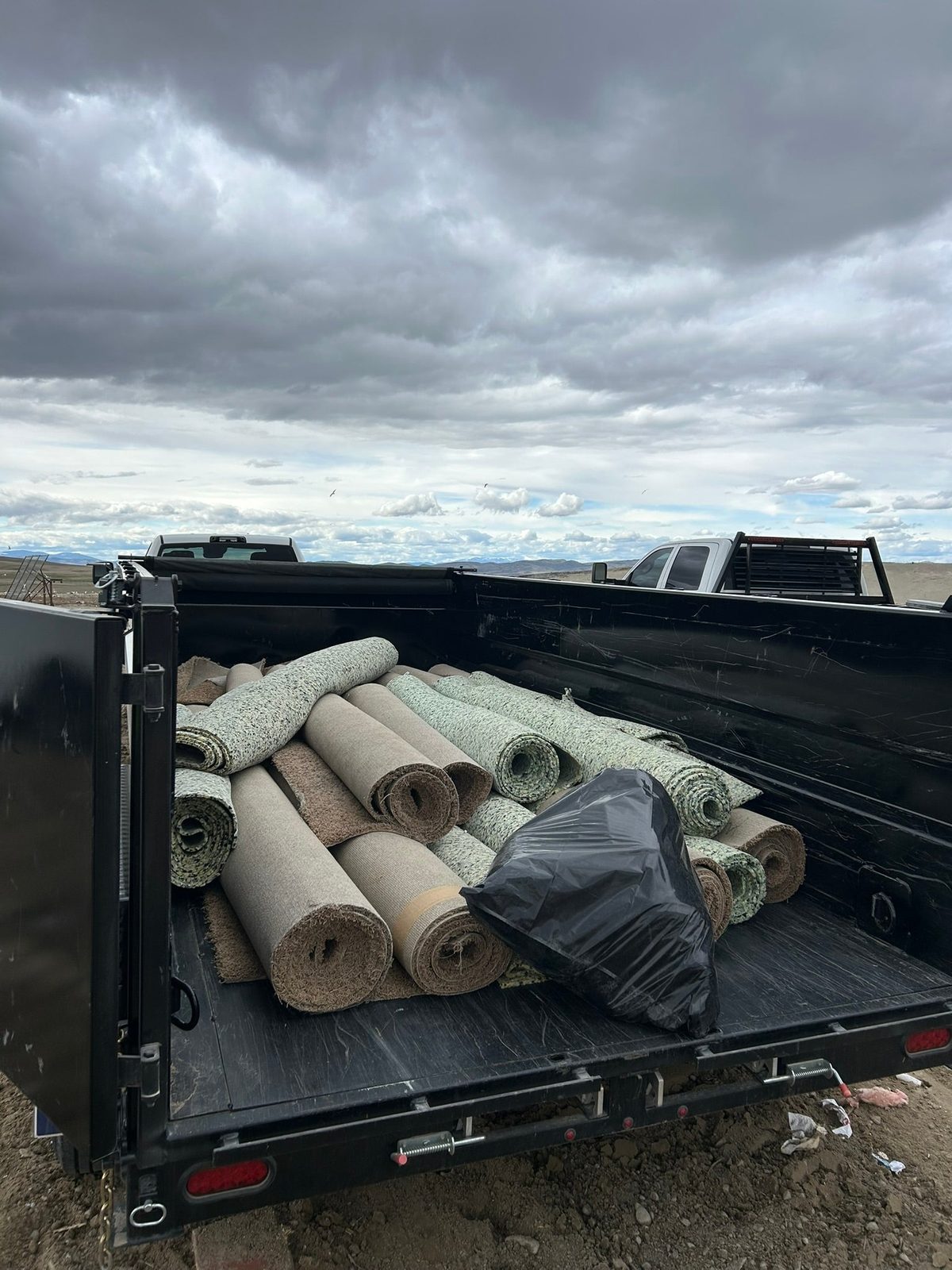 Rolled carpet and junk loaded in a dump trailer
