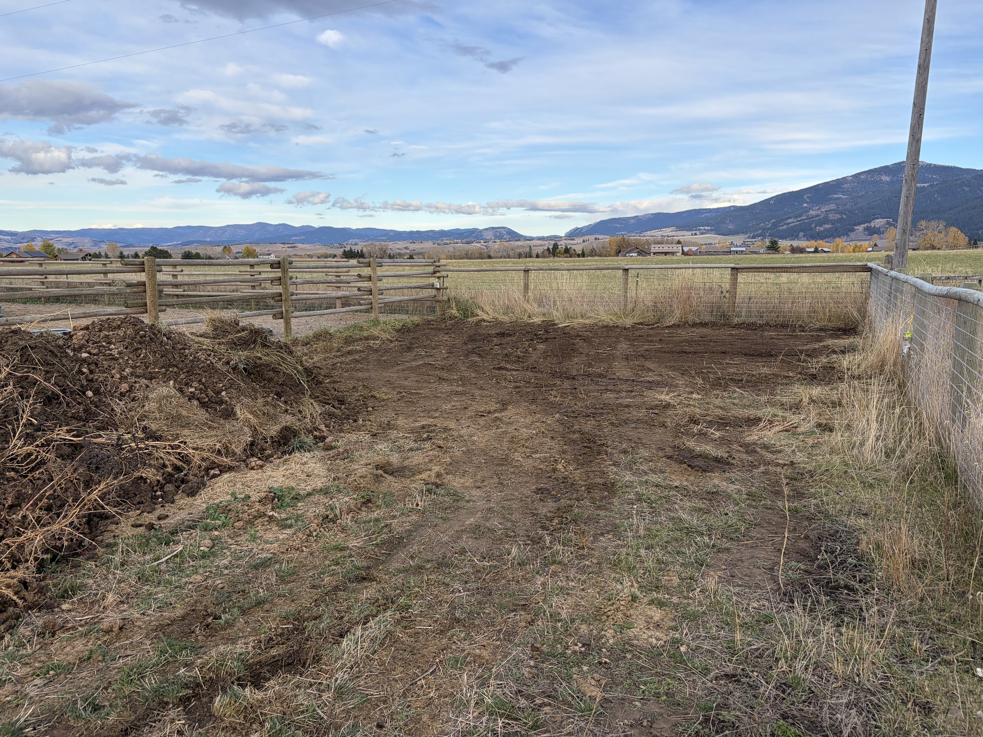 Cleared dirt pad beside a fence after a manure haul
